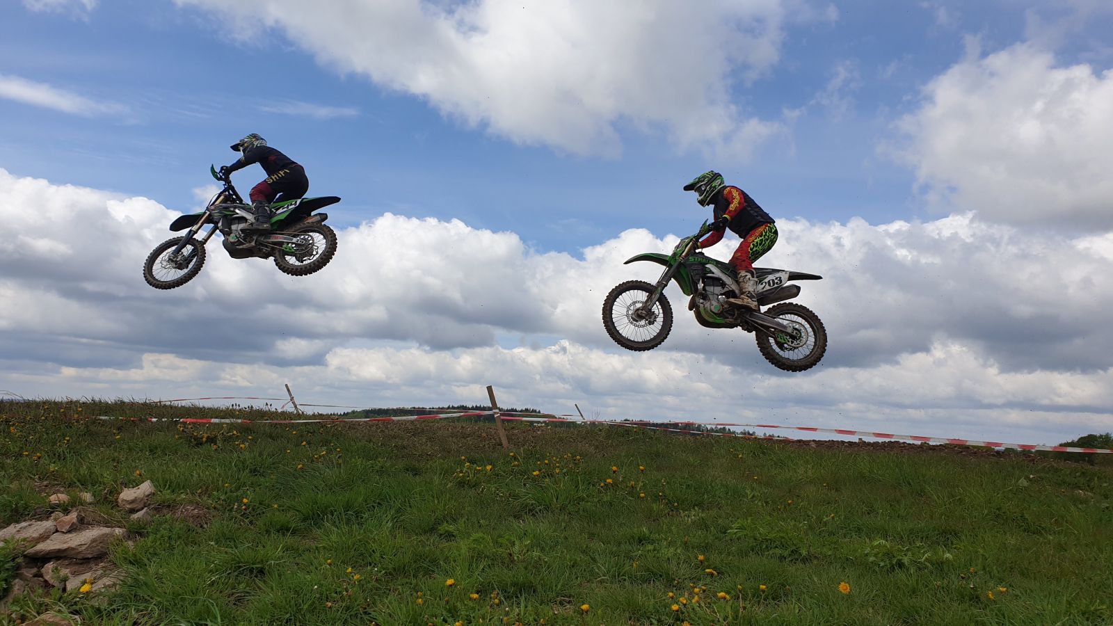 2 Motorradfahrer springen über den Berg
